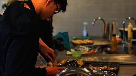 Een leerling van Aeres VMBO Nijkerk is aan het koken in de keuken van de school. 