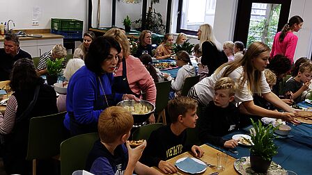 De lunch wordt uitgeserveerd aan een groep Oekraïense vluchtelingen, vrijwilligers van de buurtmoestuin en leerlingen van GBS De Open Kring 