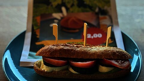 de leerlingen hebben een nieuw broodje voor de kantine ontwikkeld. Op de foto staat een pistolet met tomaat, pesto en komkommer.